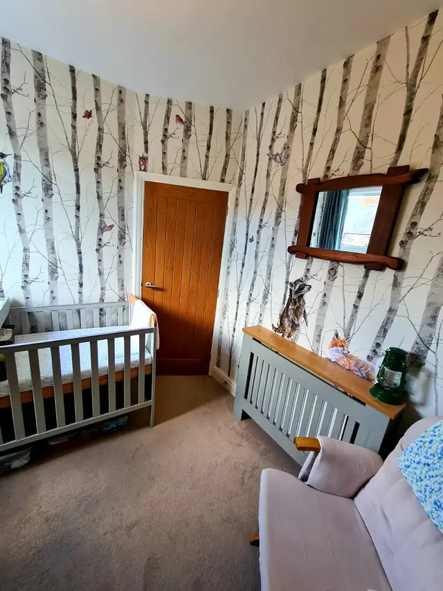 Nursery with birch tree wallpaper and a white cot