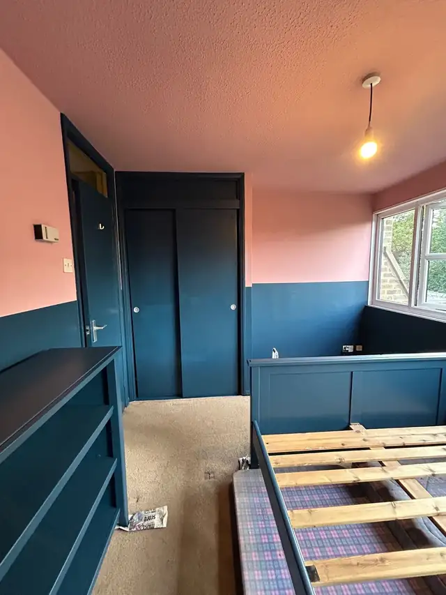 Bedroom with teal panelling, matching teal doors and pink walls