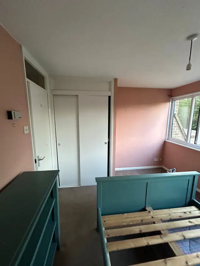 Pink walls and teal painted bed and chest of drawers